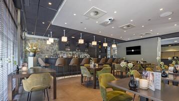 A modern hotel lobby with a bar area, seating arrangements, and a stone accent wall.
