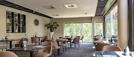 Un moderno vestíbulo de hotel con varias zonas de estar, un mostrador de recepción y grandes ventanales que ofrecen vistas al exterior.