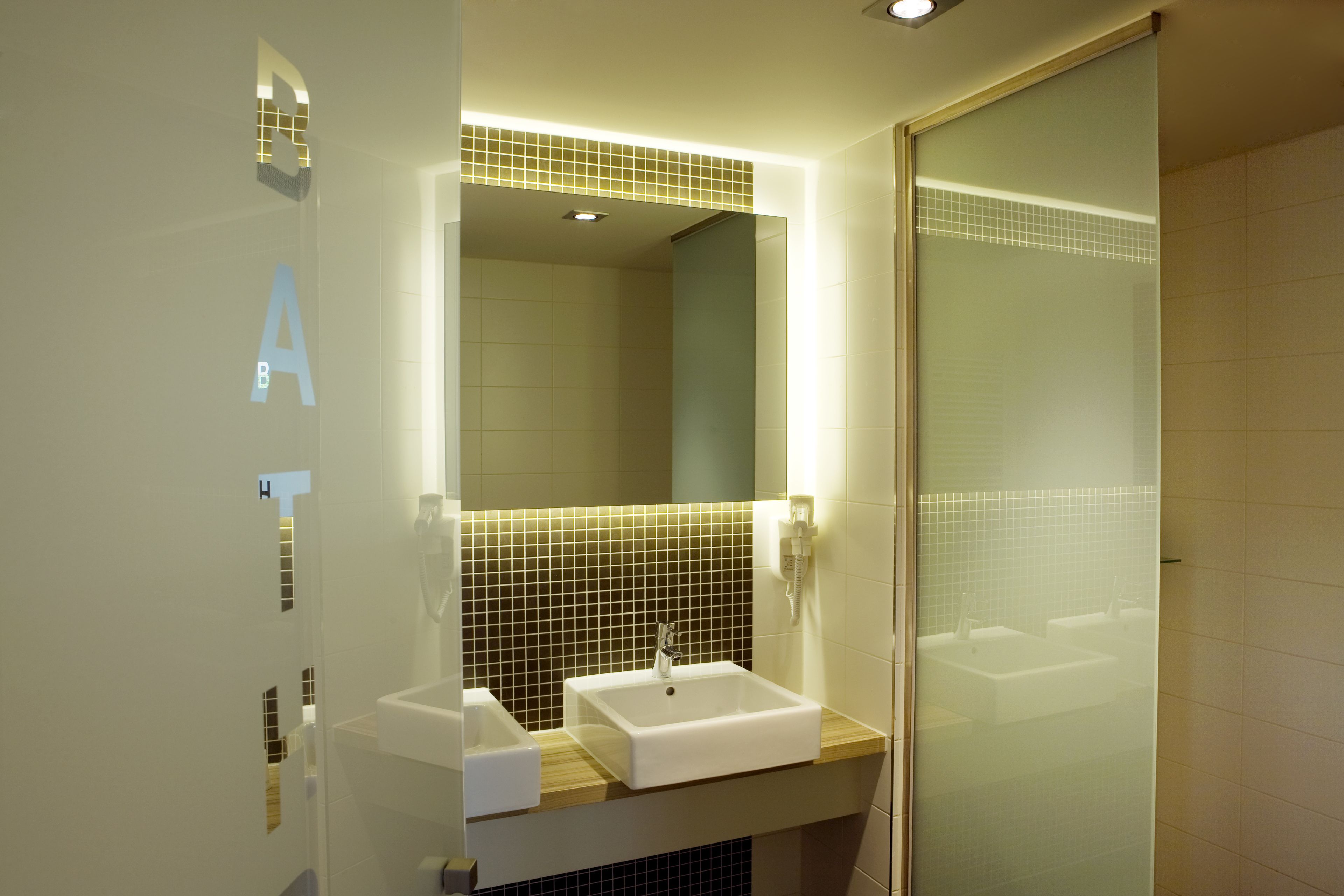 A modern bathroom with a large mirror, a sink, and a shower area.