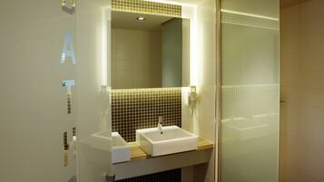 A modern bathroom with a large mirror, a sink, and a shower area.