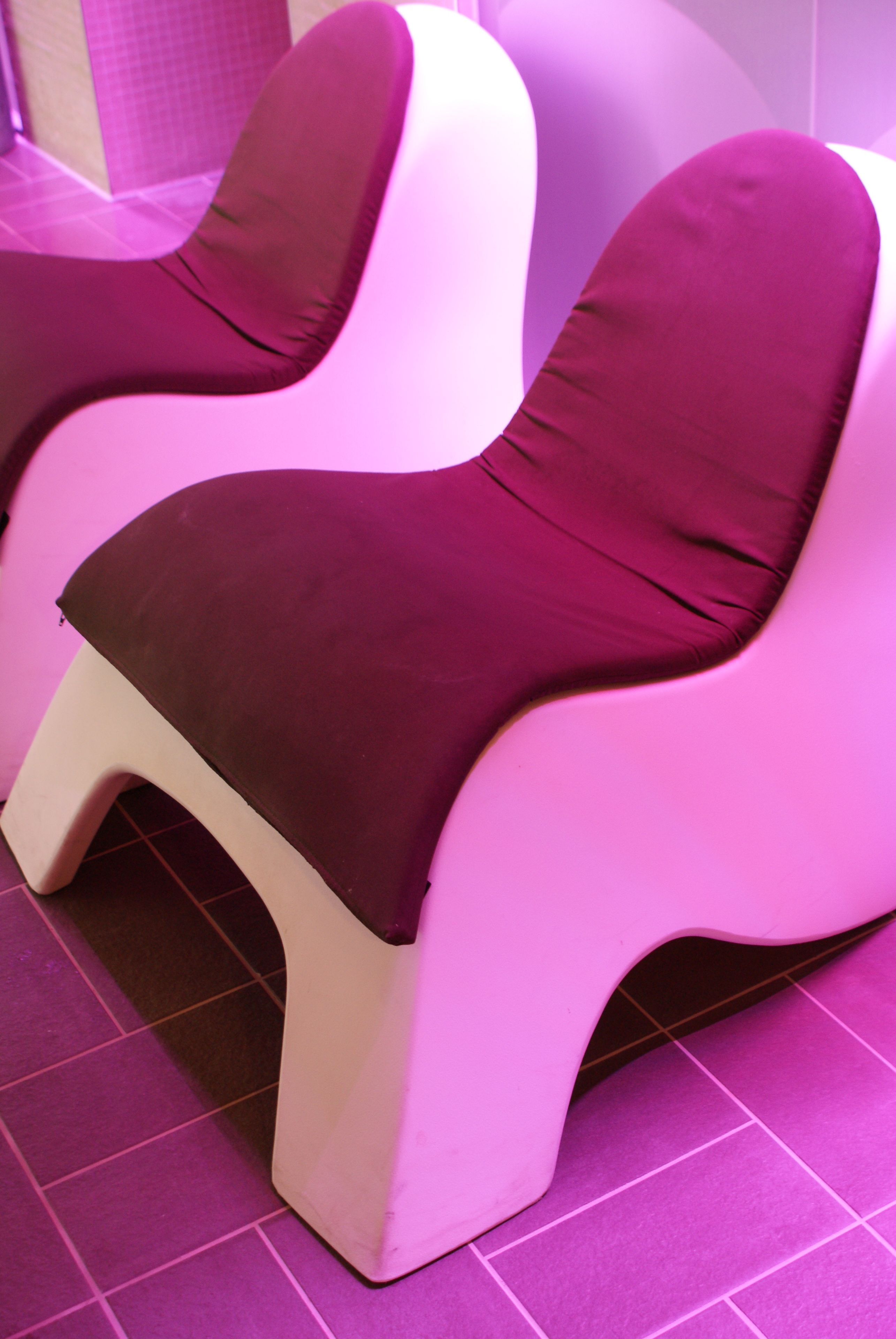 Two massage chairs with a purple and white color scheme, placed on a tiled floor.