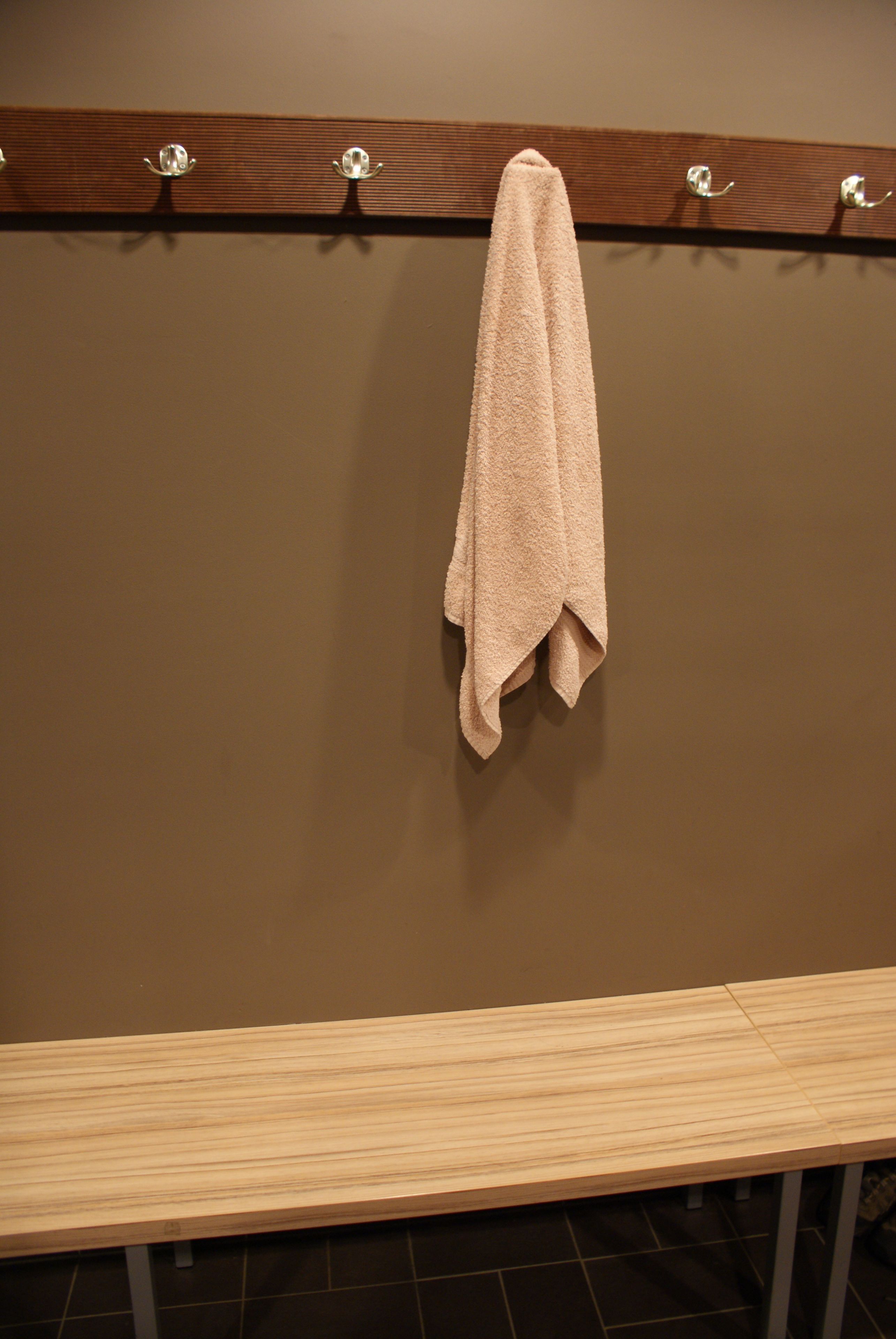 A wooden bench with a towel hanging on a metal rack.