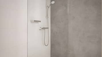 Een moderne badkamer met een douche, handdouche en bedieningspaneel aan de muur.