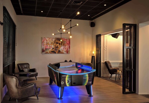 A pool table with LED lights, a modern chandelier, and a painting on the wall.