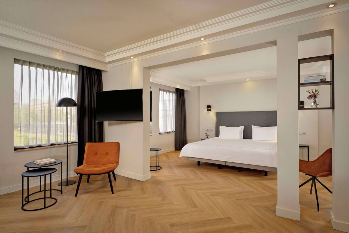 Une chambre d  ’hôtel avec un grand lit, deux fauteuils, une télévision et une petite table.