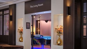 Eine Hotelhalle mit einem Billardtisch, zwei Vasen mit Blumen und einem Schild mit der Aufschrift 'The Living Room'.