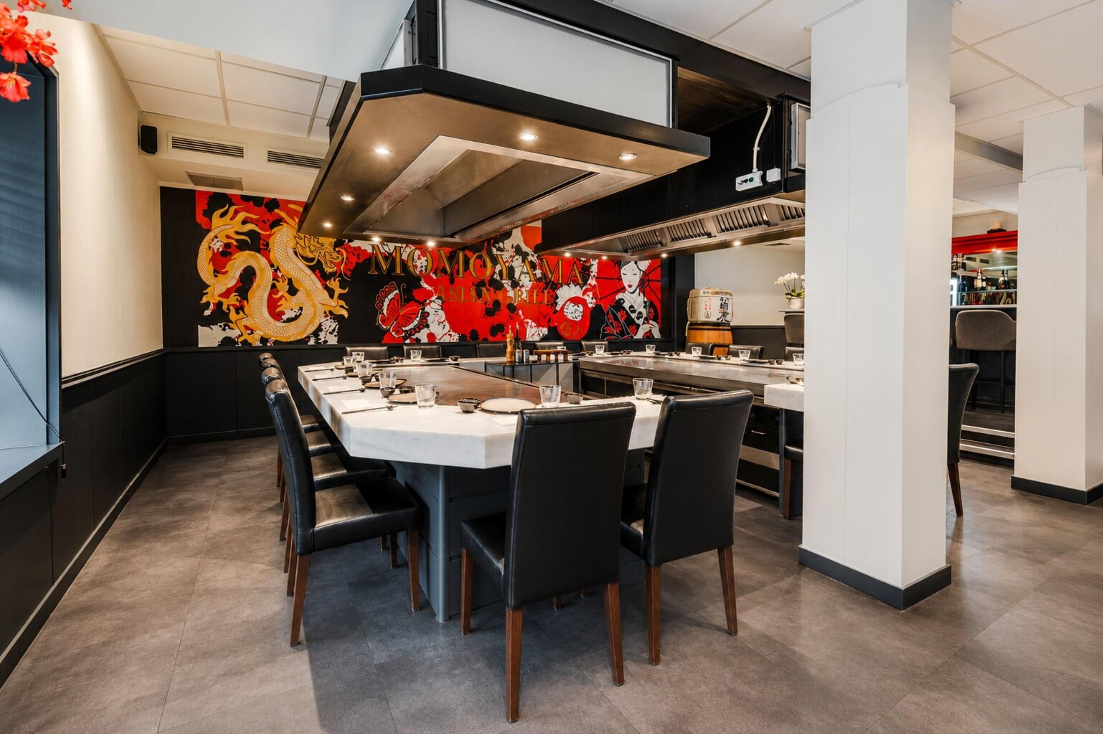 Un comedor moderno con una mesa larga, sillas negras y una pared decorativa con un diseño de dragón.