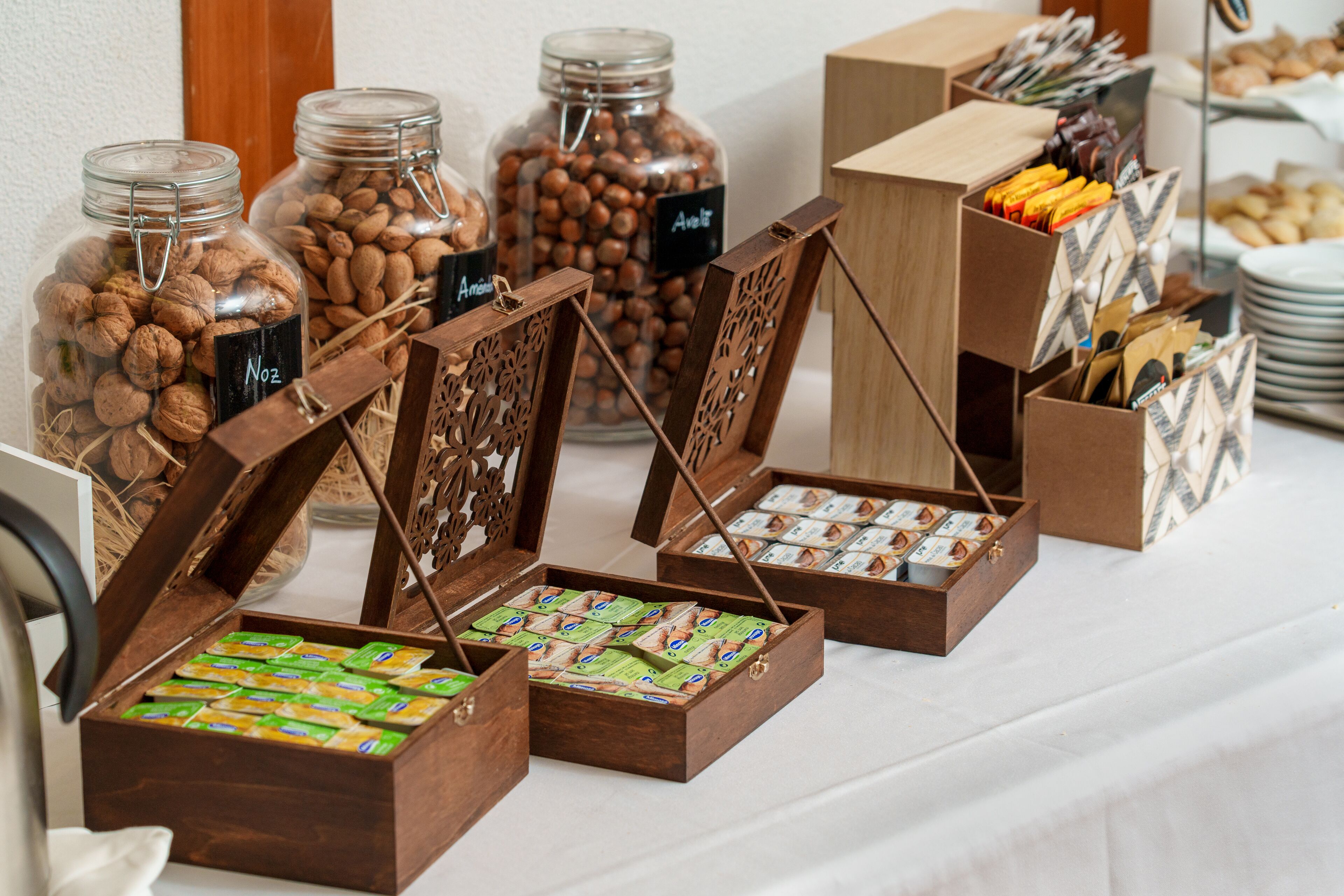 Una mesa de buffet con diversos alimentos, incluyendo frascos de frutos secos y cajas de pasteles.