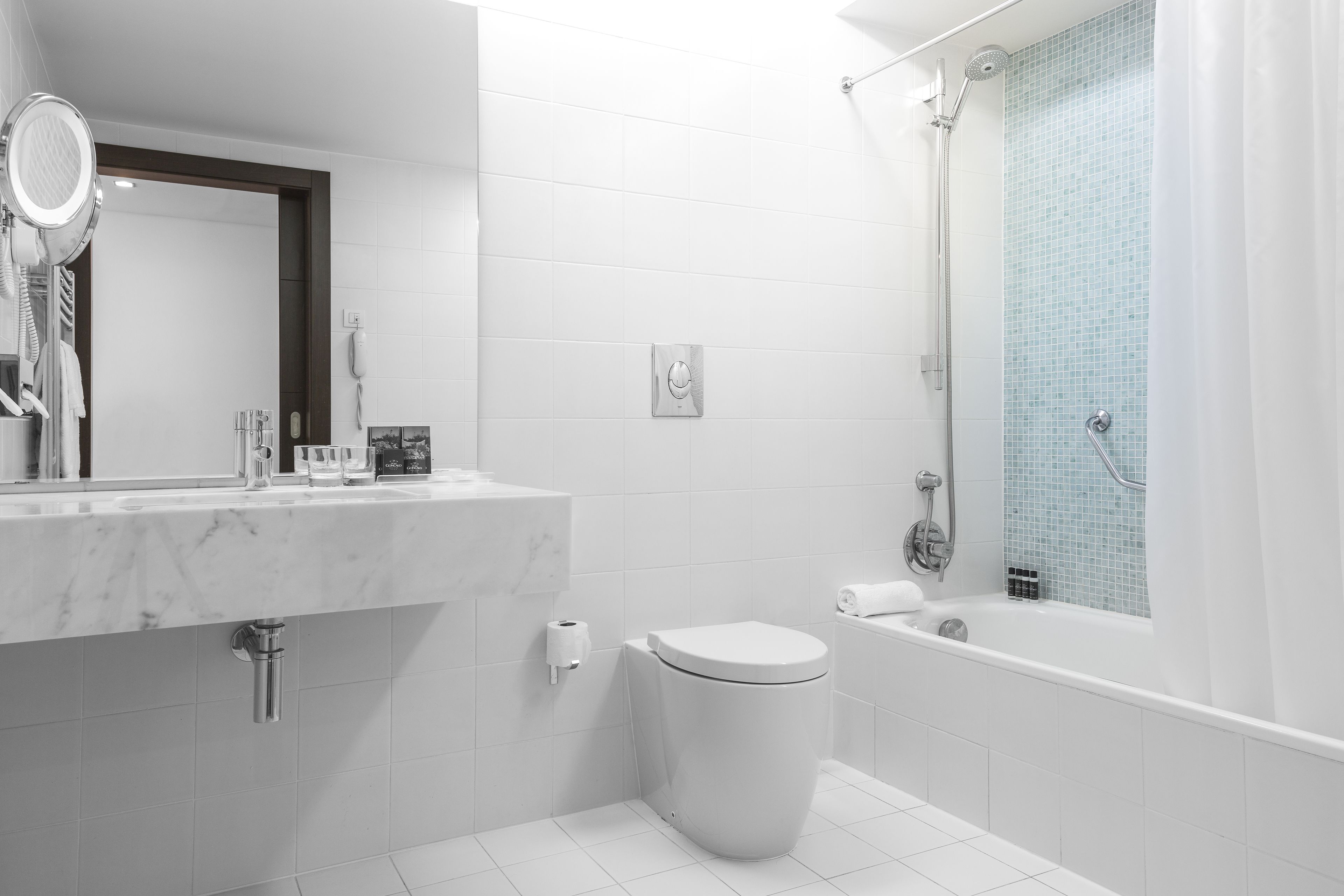 A modern bathroom with a marble sink, toilet, and bathtub.
