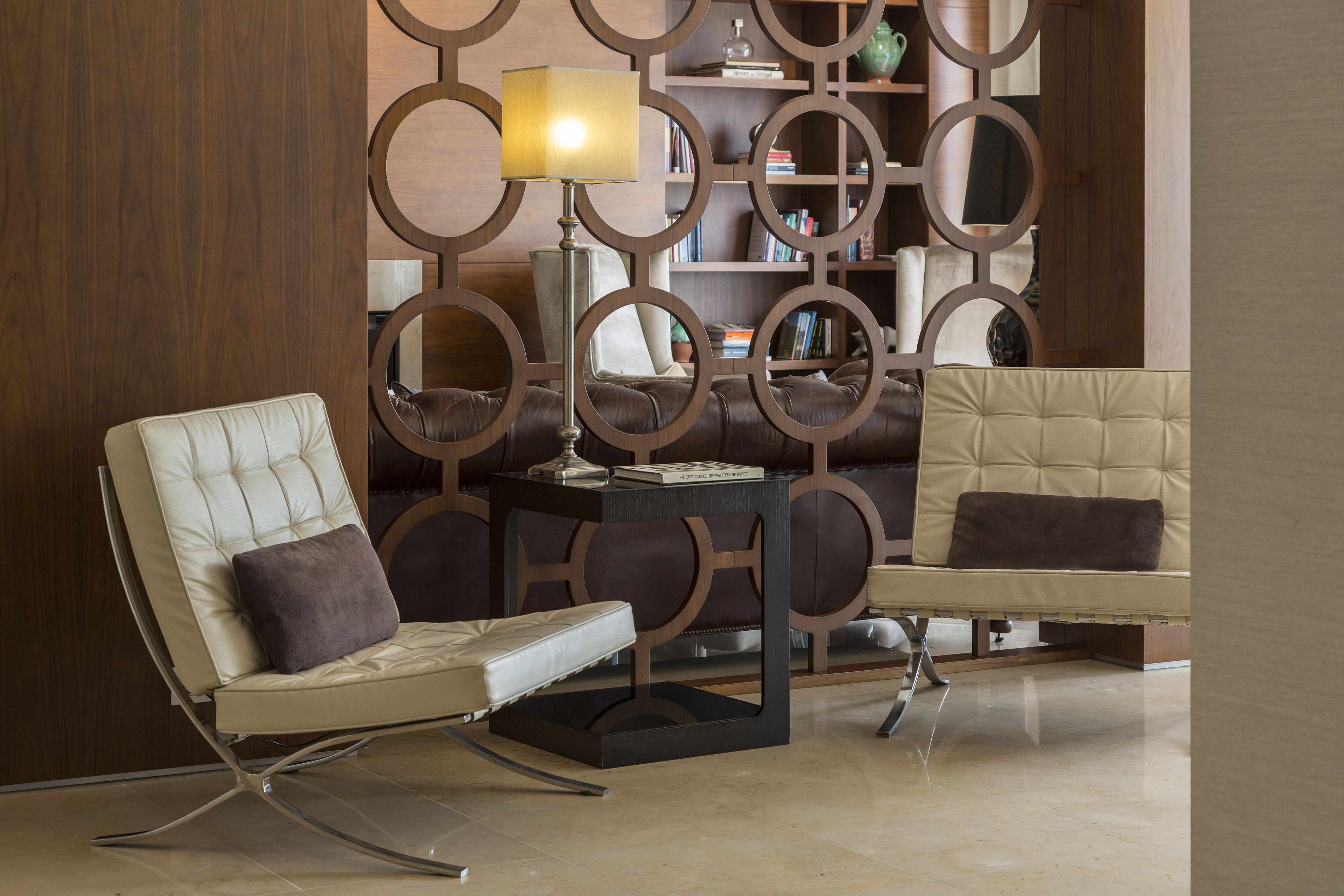 A modern living room with two leather sofas, a coffee table, and a decorative bookshelf.