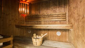 Una sauna in legno con panche, un catino di legno e una mestola, e una panca con un asciugamano.