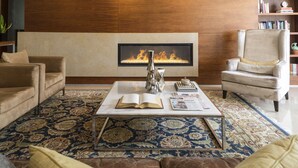 A living room with a fireplace, a coffee table with books, a sofa, and a chair. - Dom Goncalo Hotel & Spa (Ourem)