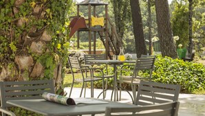An outdoor seating area with metal tables and chairs, surrounded by greenery and trees. - Dom Goncalo Hotel & Spa (Ourem)