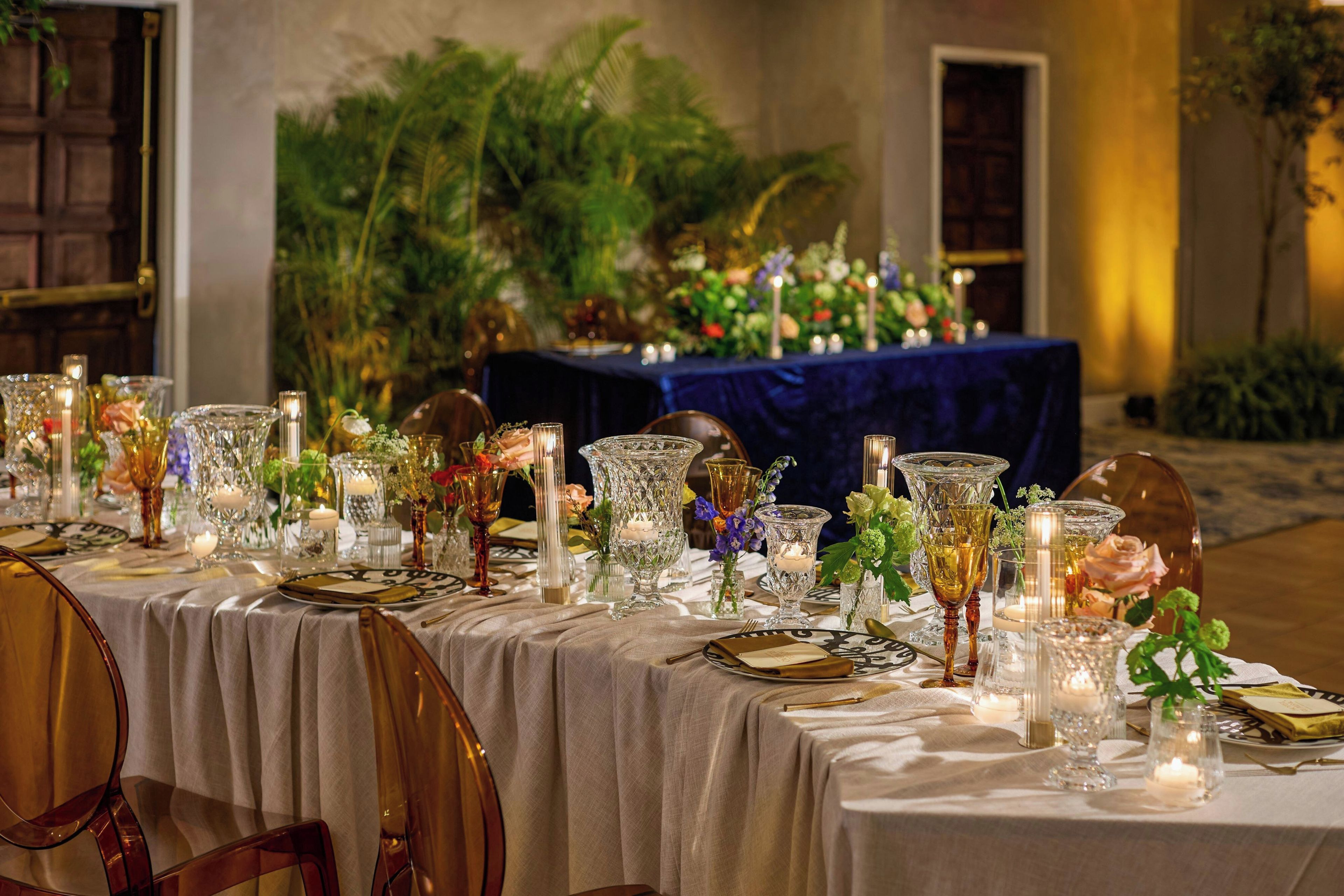 A table set for a formal event with glassware, candles, and floral arrangements.