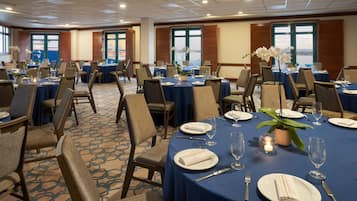 A conference room with round tables, chairs, and blue tablecloths.