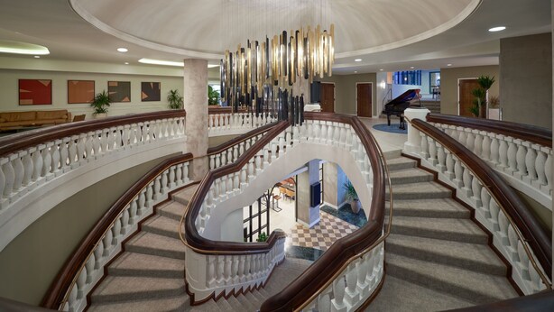 A grand staircase with a chandelier, a grand piano, and a checkered floor. - Hotel Rumbao, a Tribute Portfolio Hotel (San Juan)