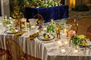 Une table à manger élégante, dressée avec de la verrerie, des bougies et des compositions florales.