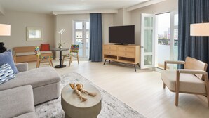 A modern living room with a sofa, armchair, TV, and a small table with a decorative item.