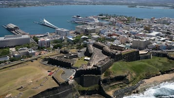 A coastal cityscape with a prominent fortification, a cruise ship docked near the waterfront, and a mix of modern and historical buildings.