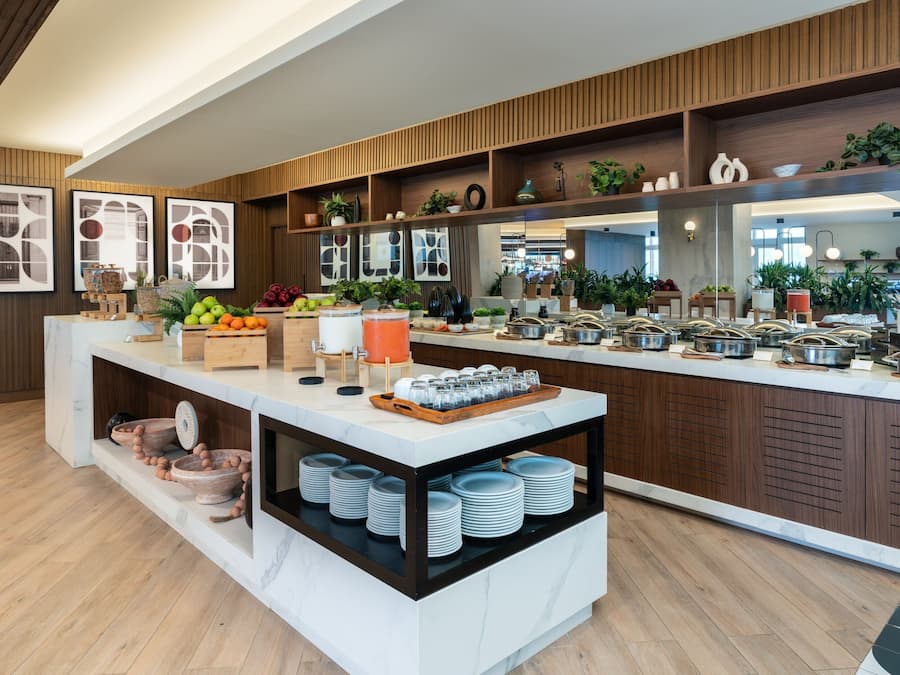 Uma cozinha moderna com bancadas de mármore, prateleiras de madeira e diversos alimentos e utensílios de cozinha.