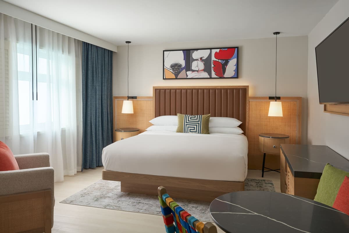Une chambre d’hôtel avec un grand lit, deux tables de chevet, un bureau, une chaise et un téléviseur.