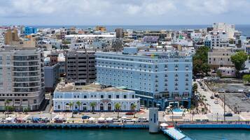 A coastal cityscape with a prominent hotel named "Hotel Rombao" featuring a central courtyard and a waterfront view.