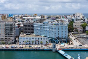 A coastal cityscape with a prominent hotel named "Hotel Rombao" featuring a central courtyard and a waterfront view.