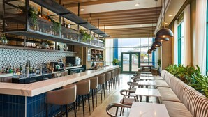 Eine moderne Bar mit einer langen Theke, verschiedenen Sitzmöglichkeiten und Blick ins Freie.