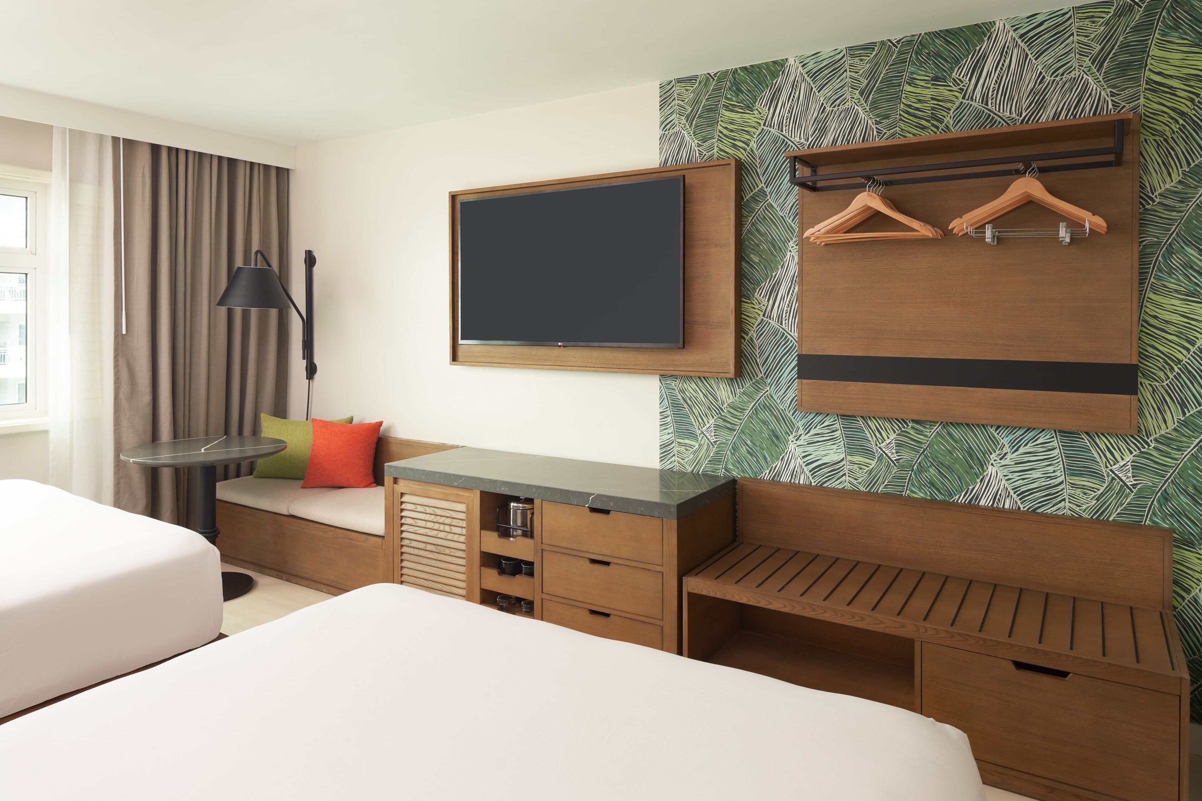 A hotel room with a bed, a desk, a TV, and a wardrobe.