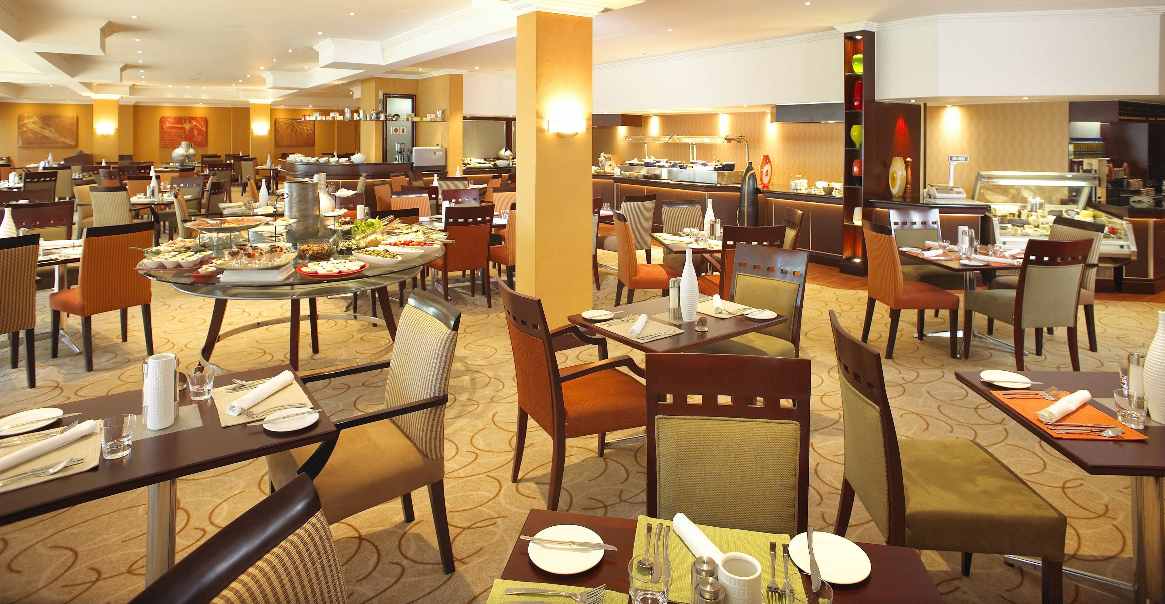 Un comedor de hotel con varias mesas, sillas y una mesa de buffet.