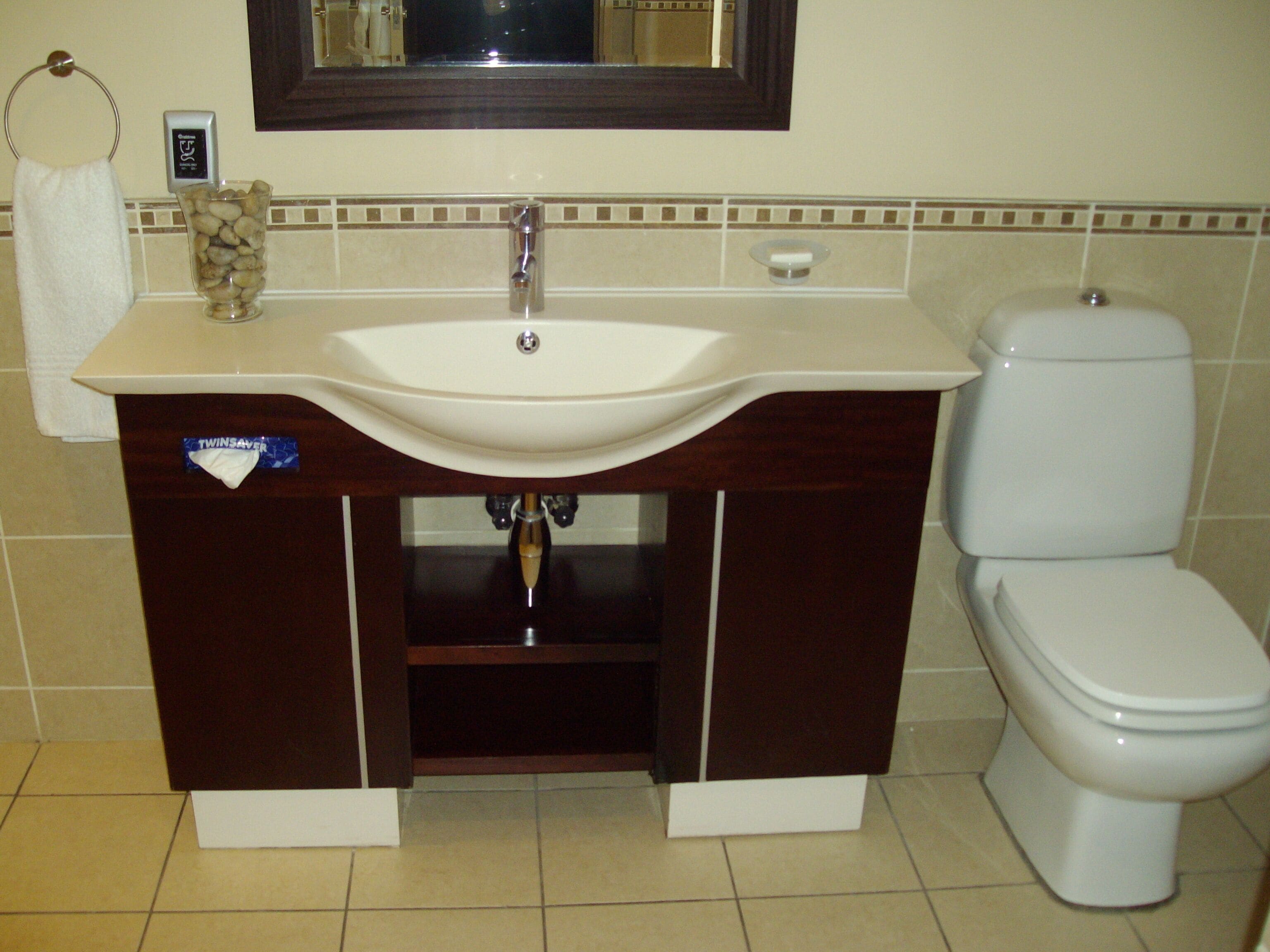 Een badkamer met een wit wastafel, een spiegel erboven en een toilet.