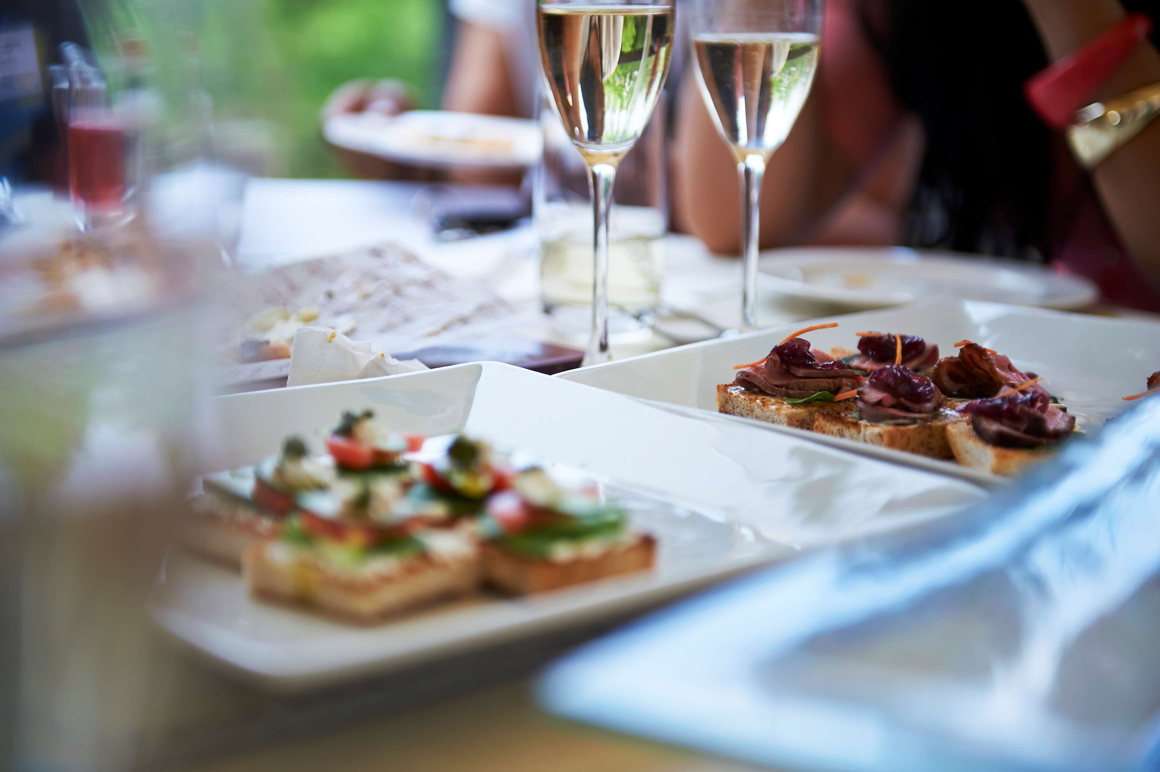 A dining table with various dishes and two glasses of white wine.