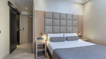 Una habitación de hotel moderna con una cama grande, una mesita de noche y un armario.