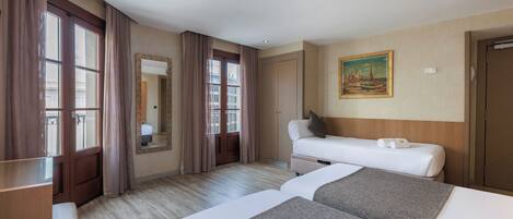 Una habitación de hotel con dos camas, un armario de madera, un espejo grande y un cuadro en la pared.