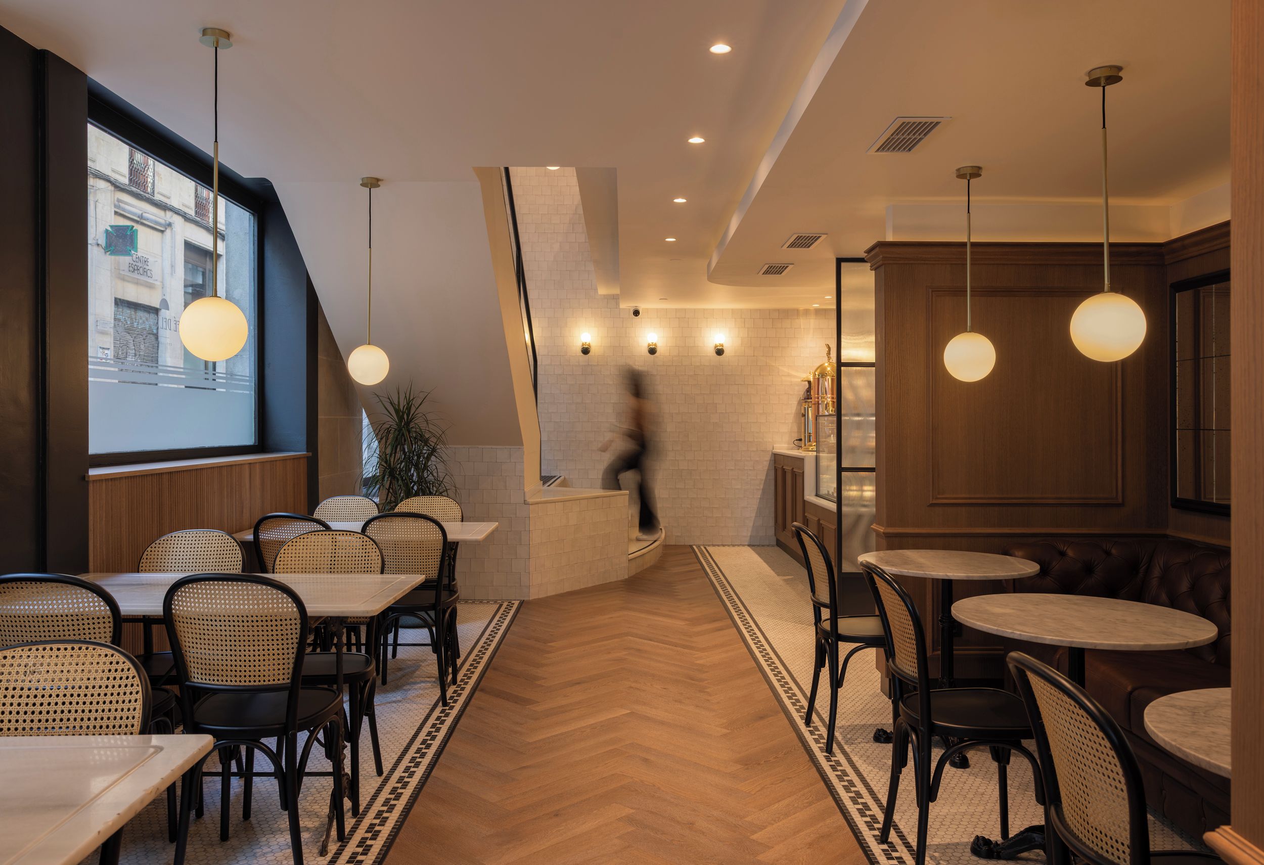 Un interior de restaurante con suelo de madera, mesas redondas y sillas.