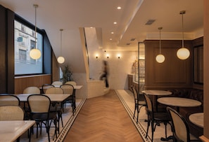 A restaurant interior with wooden flooring, round tables, and chairs. - Hotel Suizo (Barcelona)