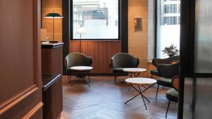 A hotel lobby with a reception desk, a large window with a view of the street, and several seating areas with tables and chairs. - Hotel Suizo (Barcelona)