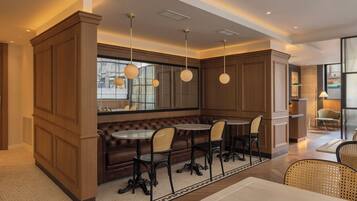 A modern interior with a central seating area featuring a brown leather bench and four chairs, a round table, and pendant lighting.