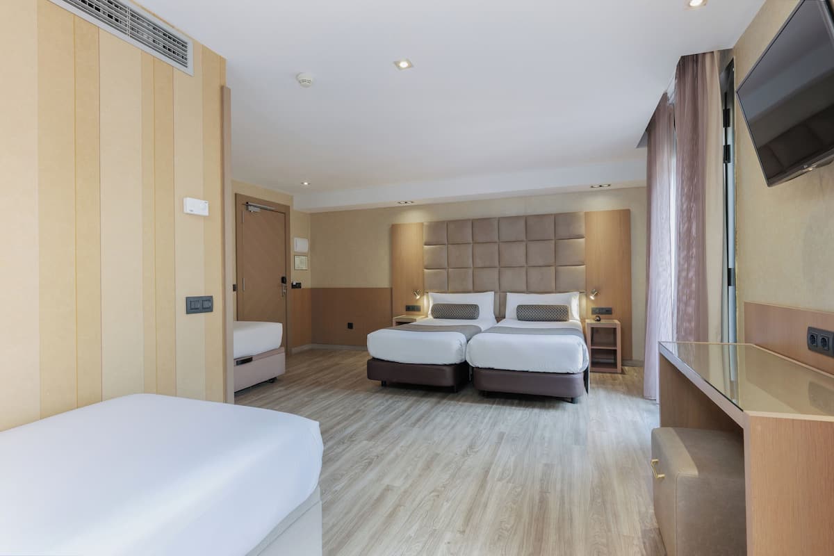 Ein modernes Hotelzimmer mit zwei Betten, einem Fernseher und einer kleinen Schreibtischzeile.