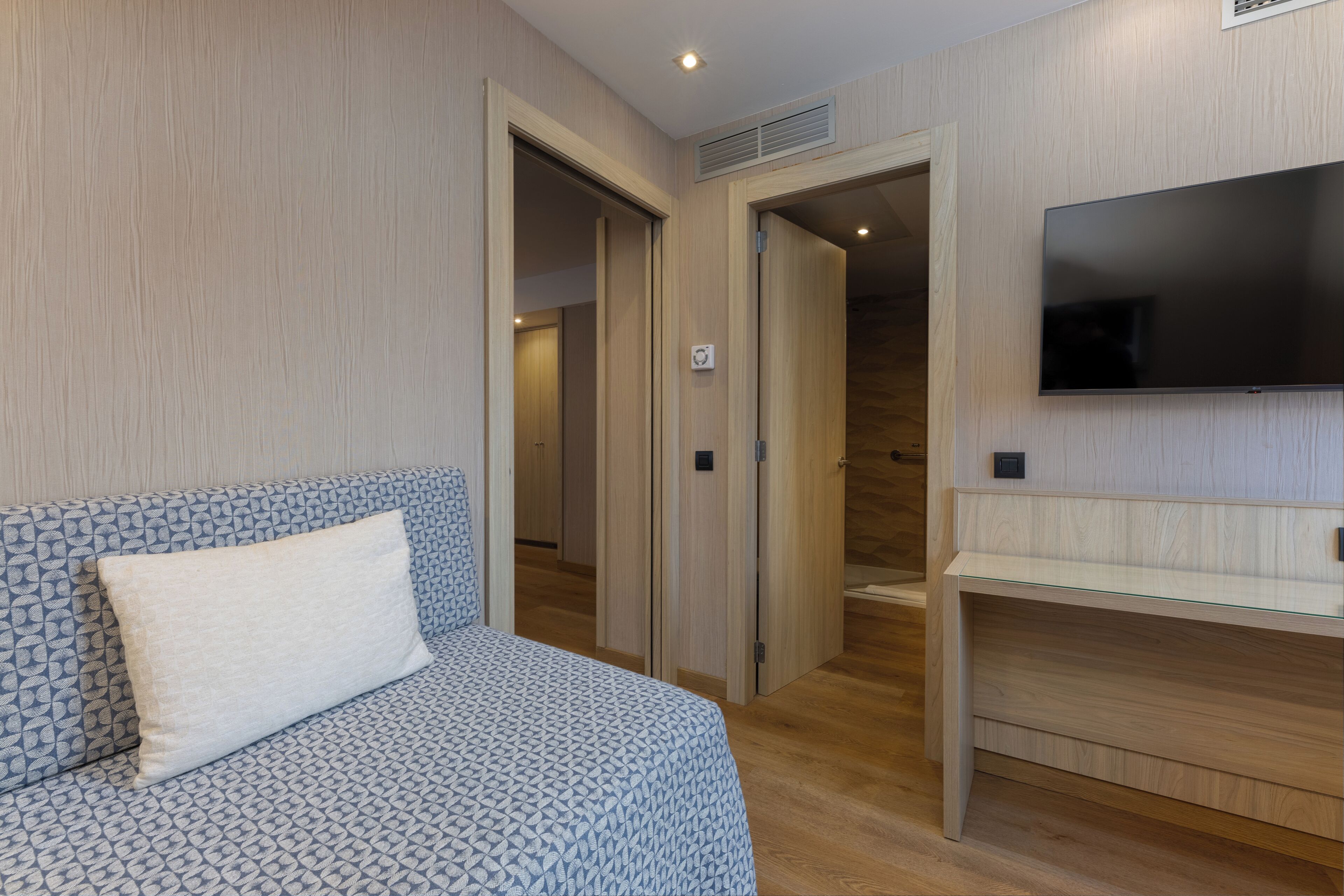 A hotel room with a bed, a TV, and a wooden wardrobe.