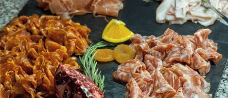 A charcuterie board with various meats, dried fruits, and citrus slices.