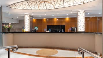A modern hotel reception area with a curved counter, a reception desk, and a decorative ceiling.