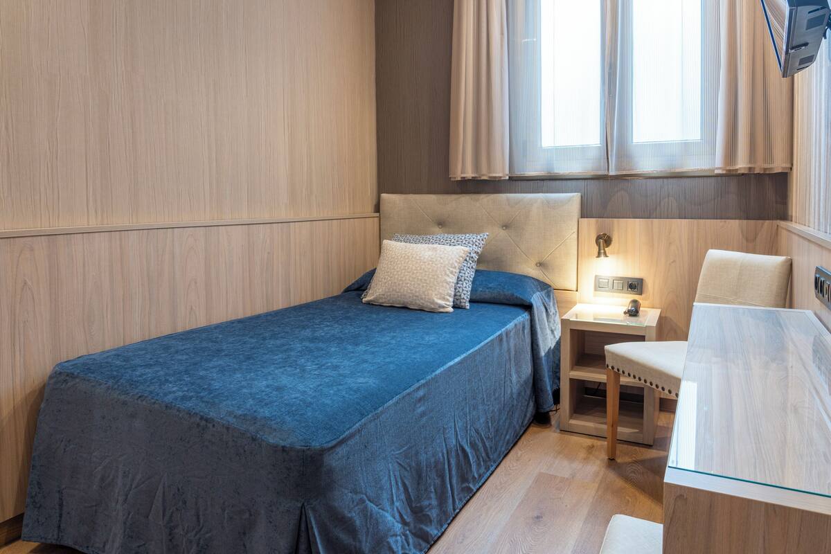 A bedroom with a bed, bedside table, and a desk.