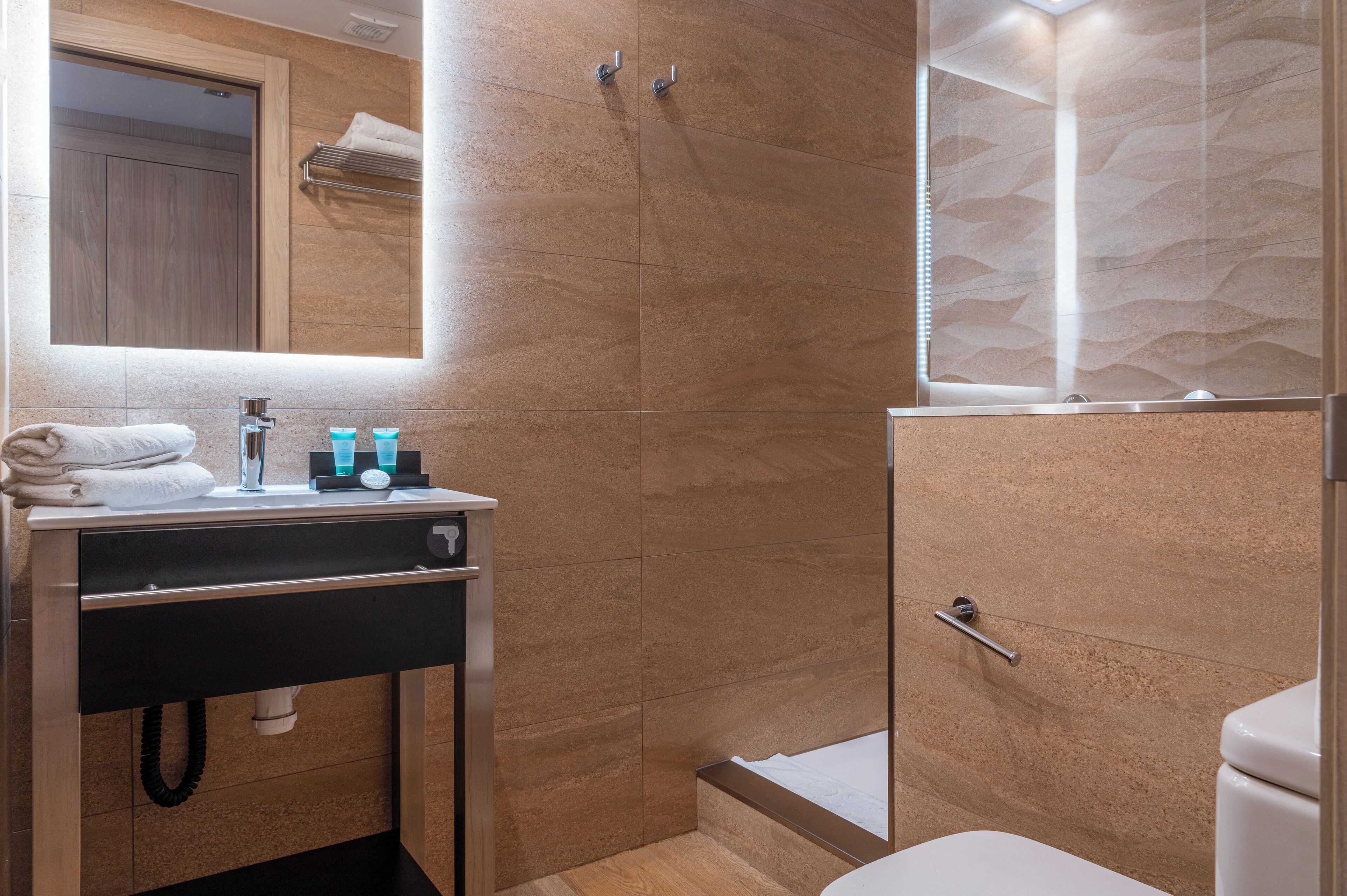 Un baño moderno con lavamanos, espejo y ducha.
