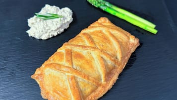 Un pastel sobre un plato de pizarra con una salsa cremosa y espárragos.