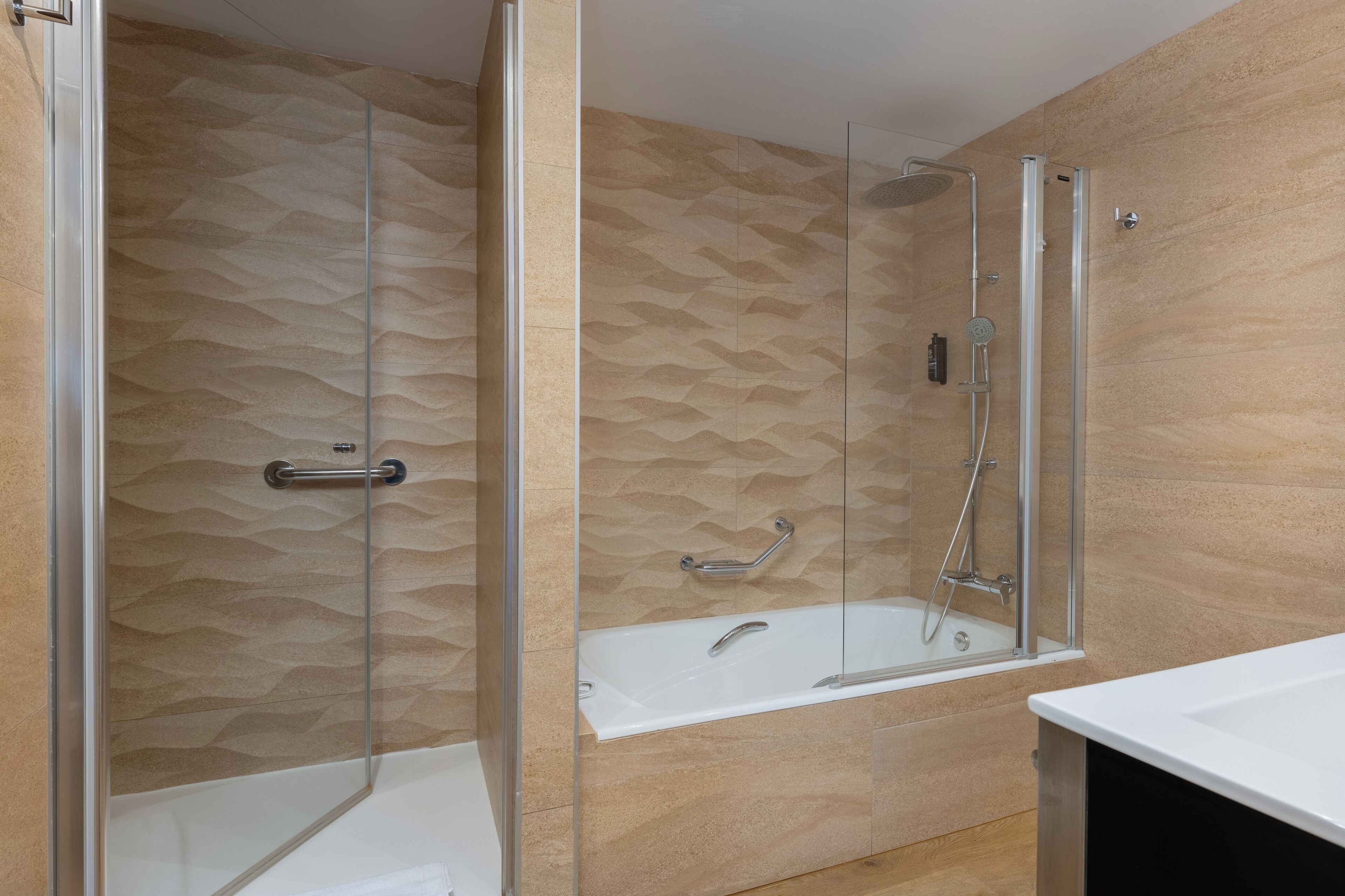 Un baño moderno con ducha envuelta en vidrio, bañera y tocador con espejo.