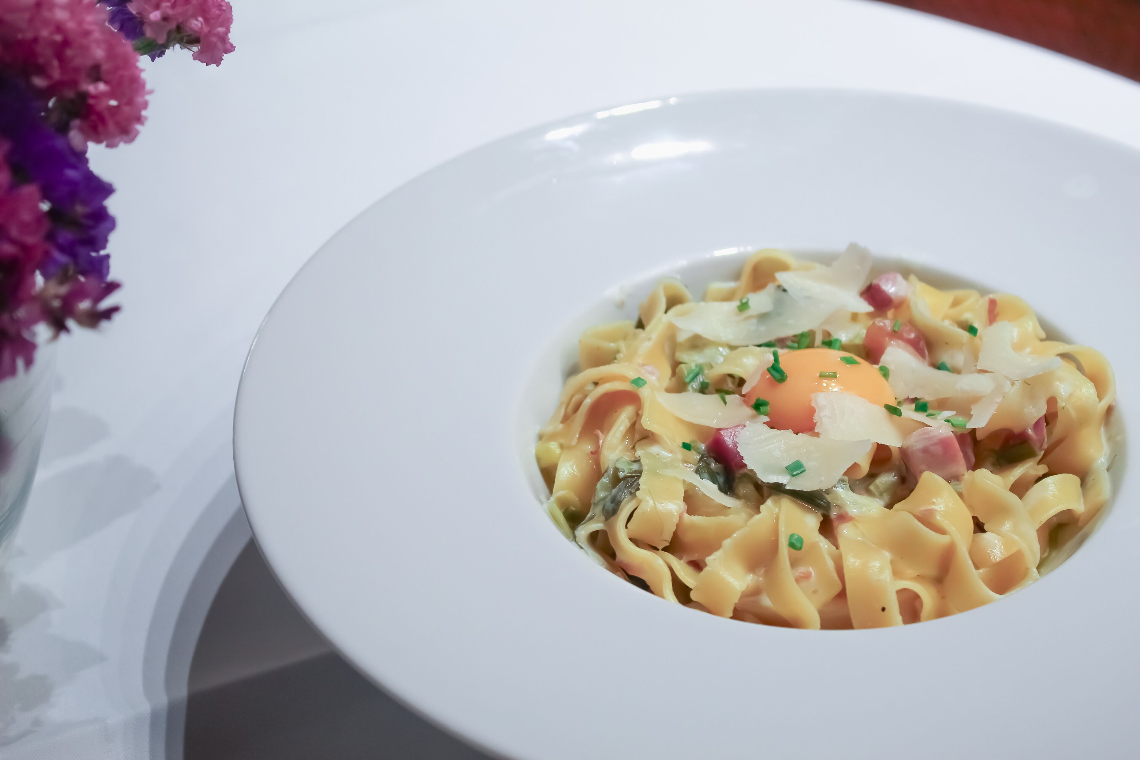 Un plato blanco con pasta, adornado con hierbas y un huevo escalfado.