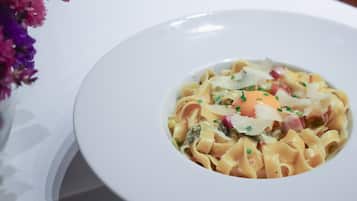 Un plato blanco con pasta, adornado con hierbas y un huevo escalfado.