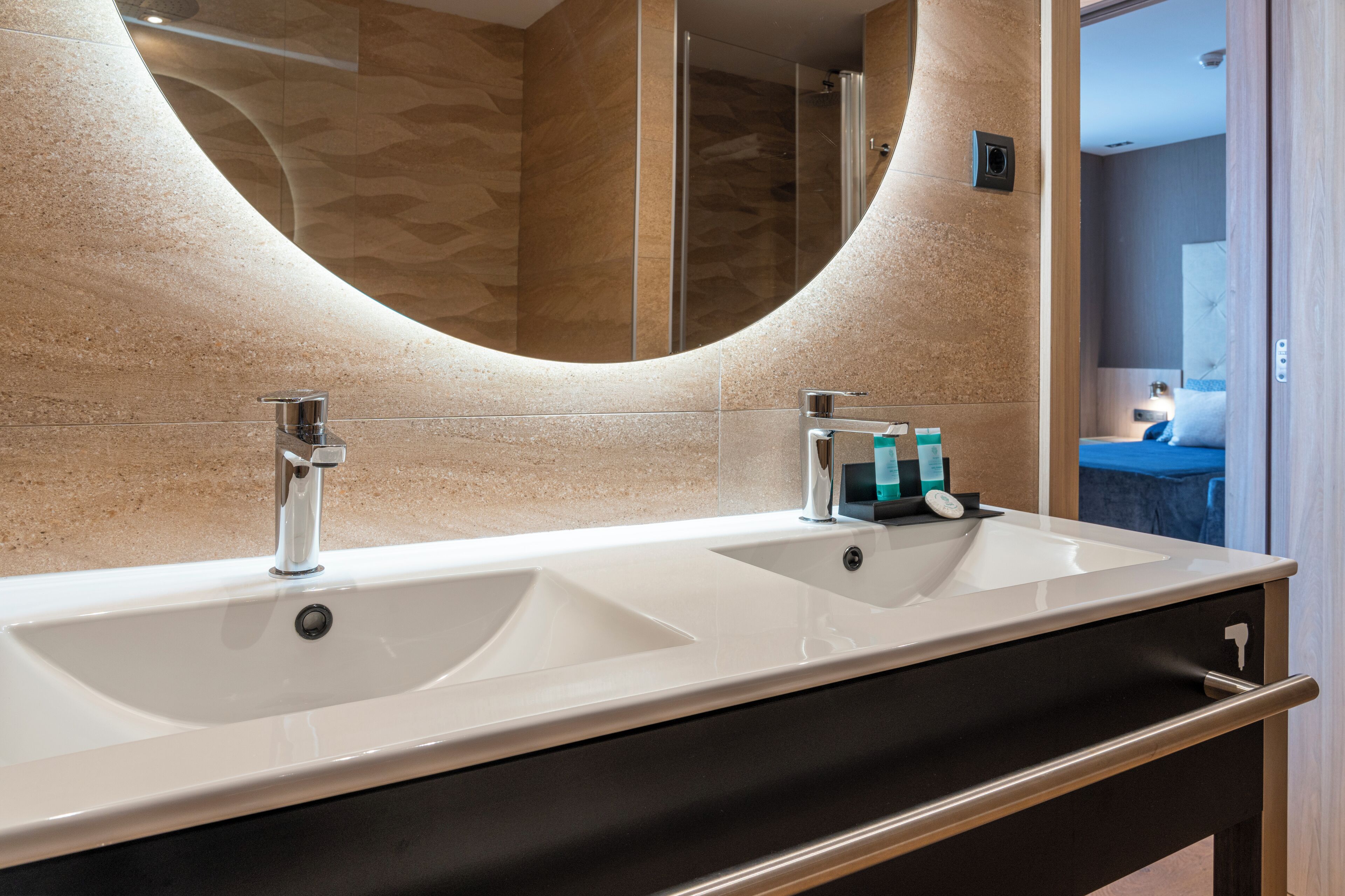 Une salle de bain moderne avec deux lavabos, un grand miroir et une douche.