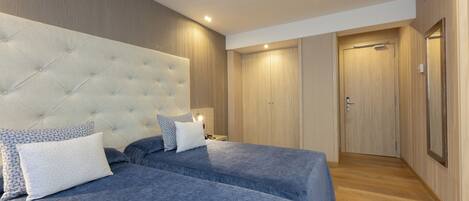 Habitación de hotel con una cama grande, dos mesitas de noche, un armario y una puerta.